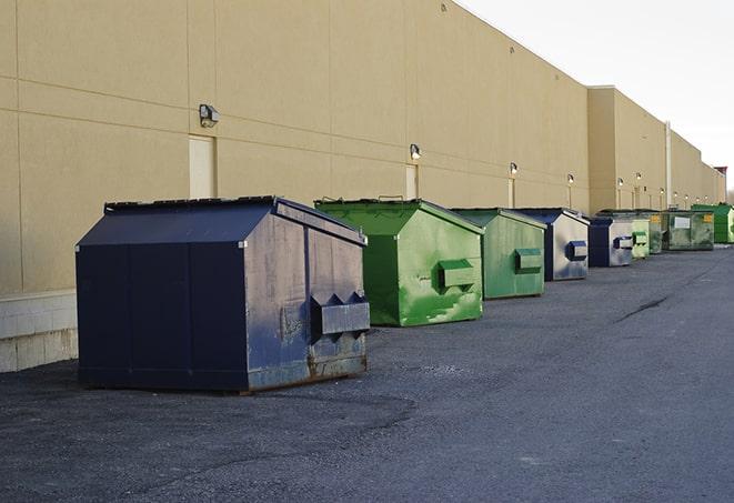 a construction worker empties a wheelbarrow of waste into the dumpster in Muskogee